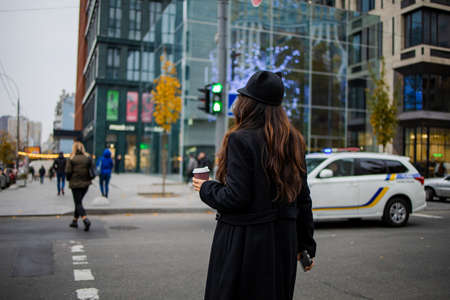 Shot of a pretty young asian woman crossing the street, holding a smartphone and looking to the side in winter time.の写真素材