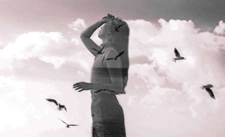 Double exposure portrait of a young woman combined with photograph of flying bird in sunset reflecting in ocean. Conceptual image showing unity of human with nature. Ecology, freedom, environmentの写真素材