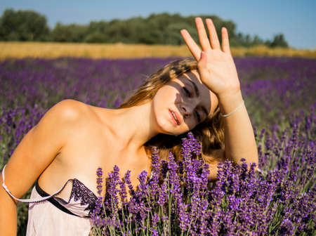 Beautiful girl in lavender wreath and retro dress on the lavender field. Beautiful woman in the lavender field on sunset in France .Girl collect lavender. soft focus.の写真素材