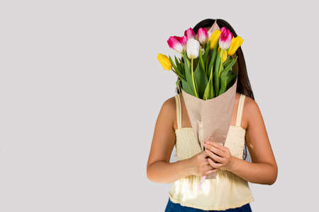 Young woman holding a bouquet of spring festive tulips in her handsの写真素材