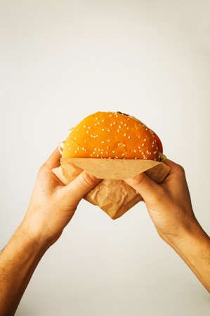 man's hand with a delicious fresh burger on a light backgroundの素材 [FY310181830784]