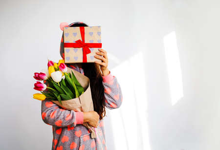 Young happy girl holding bouquet of colorful spring flowers gift box isolated on white background. women's day on March 8 or birthday.の写真素材