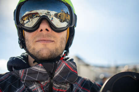 Portrait of man wearing a helmet and glasses on the background of snow winter and mounts.