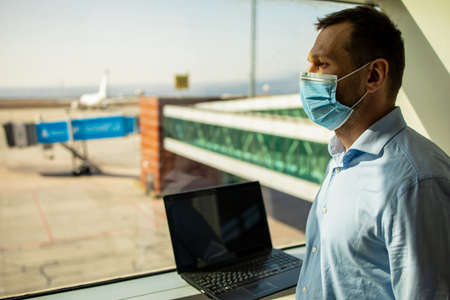 passenger businessman wear masks disease prevention and Teleconference with laptop while traveling to work abroad at the airport terminal.New normal and Business trip conceptの写真素材