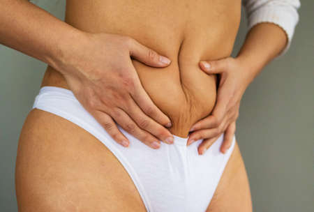 Woman in white underwear holds her belly fat.の写真素材