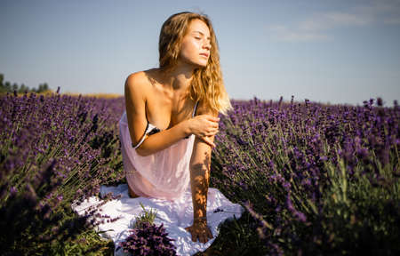 Young pretty blonde woman in lavender field on sunny summer dayの写真素材