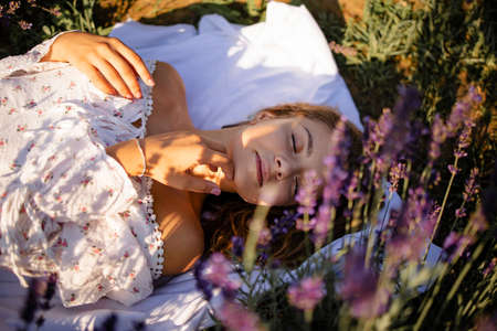Young pretty blonde woman in lavender field on sunny summer dayの写真素材