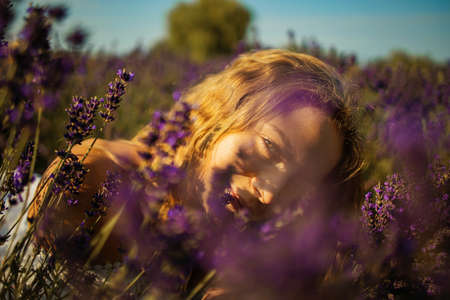 Young pretty blonde woman in lavender field on sunny summer dayの写真素材