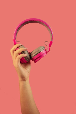 Hand holding Pink Headphones Isolated on pink Backgroundの写真素材