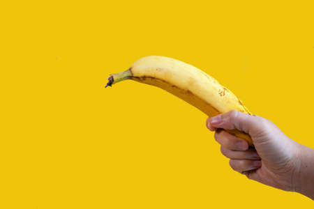 a woman holding a banana isolated on yellow backgroundの写真素材