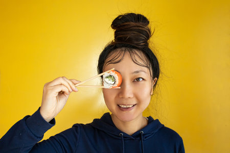 japanese girl eating sushi with chopsticks close up, food takeout and delivery service, salmon sushi rolls, tasty meal, sushi deliveryの写真素材
