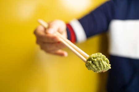 Wasabi on wooden chopsticks isolated on yellow background, copy space.の写真素材