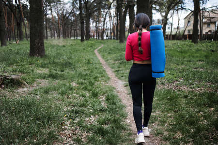 Asian attractive fitness woman in sportswear holding yoga mat at the forest