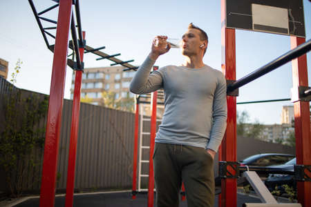 A handsome man in sports rest after workout outside on the playground, fitness, sport, lifestyle.