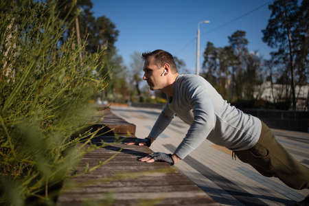 Handsome athlete doing fitness outdoor in park. Healthy lifestyle concept.