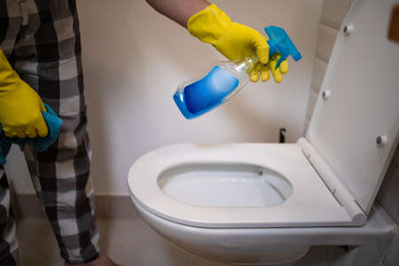 Hands on yellow gloves cleaning a WC
