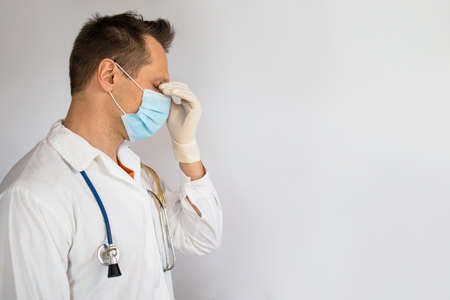 doctor man taking a break, looking tired, exhausted or sad. Wearing protective gloves, mask and...