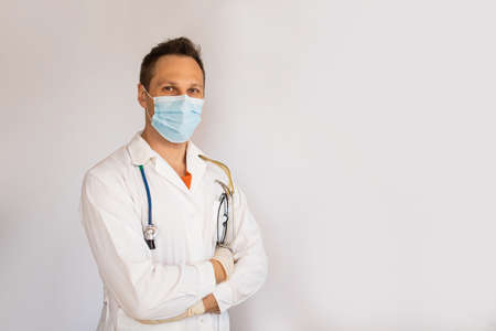 Close-up headshot of smiling young male doctor wearing white coat, isolated on gray backgroundの写真素材