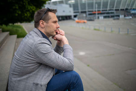 Upset stressed young business man in suit with hands on head sitting on stairs. Unemployment and...