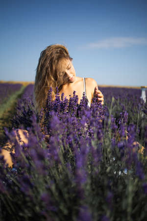 Relaxed pretty woman breathing fresh air sitting in a lavender field a sunny dayの写真素材