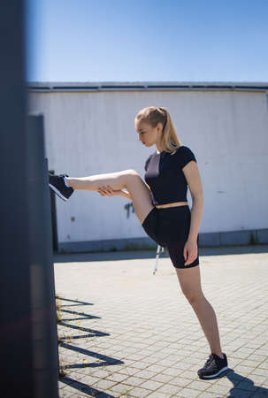 Fitness runner body close up, woman doing warm-up before jogging, stretching leg muscles, Female...