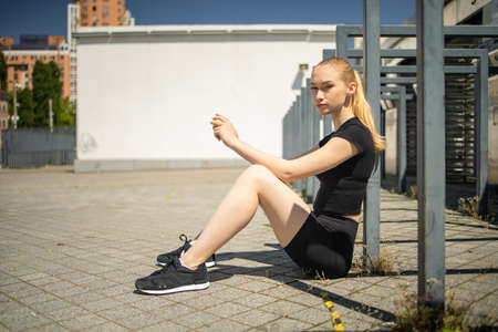 Cute young blonde woman, exercising in city outdoor trim trail station, lifestyle portrait