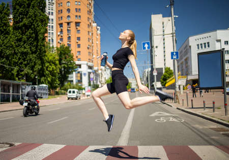 Athlete trail running woman runner silhouette in city on crosswalk. Cardio fitness training female...