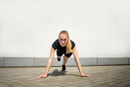 Pretty young fit woman with rubber bands exercise in urban environment.