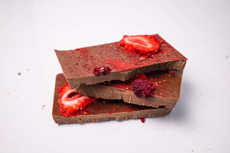 Handmade chocolate with fresh and dried berries, raspberries, strawberries on white background in...