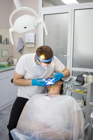 Practitioner male dentist drilling tooth to patient in dental studioの写真素材