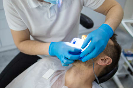 Practitioner male dentist drilling tooth to patient in dental studioの写真素材