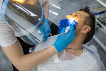 Practitioner male dentist drilling tooth to patient in dental studioの写真素材