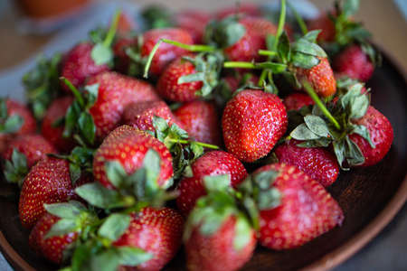 Fresh strawberries in a bowl on a wooden table.の写真素材