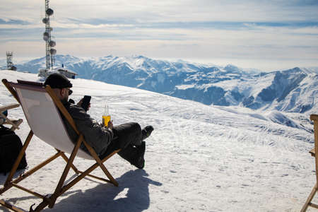 Picture from back of man in armchair, skis, sticks in snowy resortの写真素材