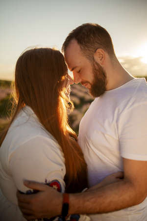 Close up portrait of a beautiful red head woman smiling and trying to kiss her boyfriend against sunset while dating outside.の写真素材