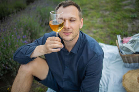 Young man drinking wine in sunset lavender field in France