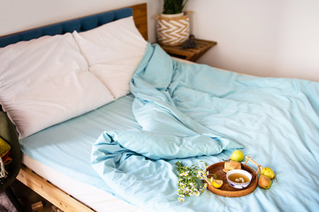 a cup of hot tea with chamomile on a tray in bed. Blue sheets with breakfast in bed.の写真素材