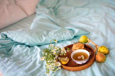a cup of hot tea with chamomile on a tray in bed. Blue sheets with breakfast in bed.の写真素材