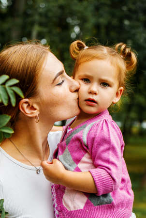 happy family. young mother kisses her cute little daughter outdoor in park.の写真素材