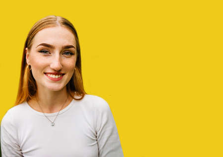 portrait of a beautiful positive red-haired girl with arrows on the eyes isolated on yellow background.の写真素材