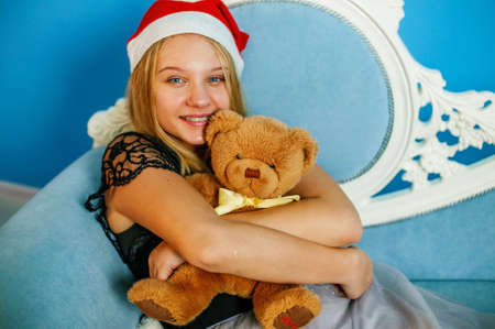 Portrait of cute teen girl with small teddy bear in hands on Christmas backgroundの写真素材