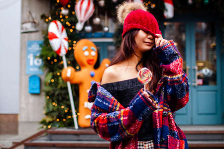 Street portrait of friendly positive smiling asian lady holding christmas decoration on winter cityの写真素材