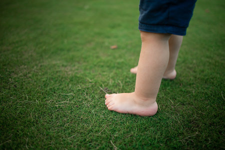 boy feet in nature. bare feet in the green grass. little happy child running at sunset barefoot outdoor. concept of happy childhoodの写真素材