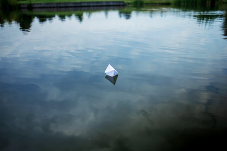 White paper boat sailing on blue water surface of lake.の写真素材