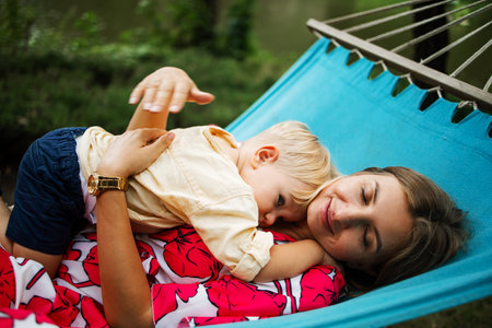 Young mother and little son in the park in the spring at sunset. happy family. weekend playtime conceptの写真素材