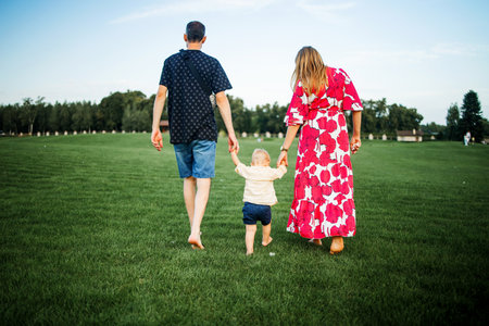 Happy family with little child in the park at sunset.