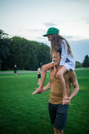 father carrying his young daughter on his shoulders. happy loving family. Father and daughter girl playing and hugging outdoors. father's day concept.の写真素材