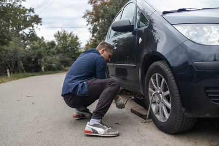 A man changes a wheel after a car breaks down. Transport, travel conceptの写真素材