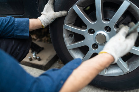 Auto mechanic man with electric screwdriver changing tires outside. car service. Hands replace tires on wheels. Tire installation concept.の写真素材