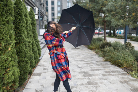 Woman trying to hold her umbrella in strong wind
